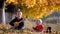 Portrait of amusing child sing at guitar to baby brother in autumn park