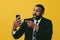 portrait of angry expressive bearded gentleman in suit and tie with smartphone video call pointing finger at camera