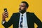 portrait of angry expressive bearded man in suit and tie with smartphone video call yellow background