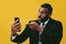 portrait of angry expressive excited bearded man in suit and tie with smartphone video call pointing finger at camera