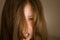 Portrait of an angry little girl with long hair. Frightening children`s eyes. Black magic and sorcery. The young witch is furious
