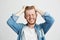 Portrait of angry rage young man touching his hair clenched teeth over wite background. Closed eyes.