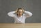 Portrait of angry stressed young woman sitting at desk, holding her head and screaming