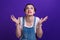 Portrait of annoyed angry woman holding hands in furious gesture over purple background.