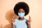 Portrait of anxious african woman holding fingers crossed wear medical respiratory mask isolated beige color background