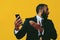 portrait of anxious expressive bearded man in suit and tie with smartphone video call pointing hand at camera yellow