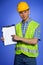 Portrait of architect in coveralls and hardhat pointing at clipboard