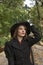 Portrait of aristocratic woman in black hat with veil looking up, in autumn park. Middle-aged woman in vintage retro style