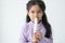 Portrait of Asian 6 year old girl, in casual clothes with black long hairs. Cute little girl eating pastel marshmallows sweet soft