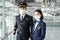 Portrait of Asian airliner pilot and air hostess wear mask and smile. Attractive man and woman captain and cabin crew stewardess