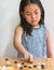 Portrait Asian child girl plays Go, the Japanese board game or Chinese board game, focus on the board game, white wall, vertical