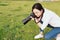 Portrait of a Asian Chinese nature woman photographer look at her camera screen in a spring park forest surround by flowers