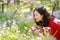 Portrait of a Asian Chinese nature woman smell flower and listen to music in a spring park enjoy free time