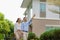 Portrait of Asian couple walking and hugging together looking happy in front of their new house to start new life. Family, age,