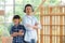 Portrait of Asian father and boy with mechanic headphone stand in front of woodwork and look at camera