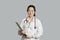 Portrait of an Asian female doctor holding a clipboard over gray background