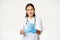 Portrait of asian female doctor, nurse in rubber gloves, giving sterile medical face masks and smiling, measures to