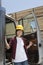 Portrait of an Asian female industrial worker standing by vehicle door