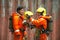 The portrait of Asian firefighters are wearing orange fire protection uniform mask and helmet front of building.