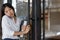 Portrait of Asian girl enter door to coffee shop .Businesswoman using phone and walking to cafe.