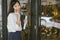 Portrait of Asian girl enter door to coffee shop .Businesswoman using phone and walking to cafe.