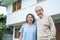 Portrait of Asian happy Senior elderly couple stand outdoor at house enjoy retirement life together. Loving Older grandparent hug