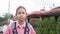 Portrait Asian high school girl in uniform with backpack wears earphones posing and looking at camera