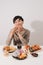 Portrait of asian man sitting and snacking donuts isolated over white background. Fat man diet concept