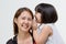 Portrait of Asian mother whispering to her daughter