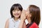 Portrait of Asian mother whispering to her daughter