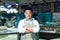 Portrait of Asian salesman in seafood and fish shop man smiling with arms crossed and looking at camera