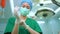 Portrait of Asian surgeon with medical mask standing and wearing medical gloves in operation theater at a hospital. Team of