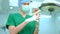 Portrait of Asian surgeon with medical mask standing and wearing medical gloves in operation theater at a hospital. Team of