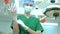 Portrait of Asian surgeon with medical mask standing and wearing medical gloves in operation theater at a hospital. Team of