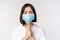 Portrait of asian woman in medical face mask from covid, begging, asking for help, say please, standing over white