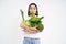 Portrait of asian woman, munching lettuce, holding green organic vegetables, on a diet, white background