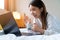 Portrait of Asian woman wearing bathrobe using a laptop on the bed