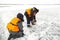 Portrait of assemblers in orange vests on the ice of the lake at the marking
