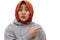 Portrait of astonished Asian muslim woman iwearing hijab feeling amazed and pointing to the side on copyspace