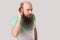 Portrait of attentive middle aged bald man with long beard in t-shirt standing with serious face, holding hand on ear and try to