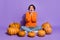 Portrait of attractive amazed cheerful girl sitting among pumpkins sale reaction isolated on vivid purple violet color