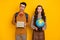 Portrait of attractive amazed funky couple holding in hands academic materials globe country isolated on bright yellow
