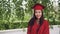 Portrait of attractive Asian girl successful graduating student in gown and mortar-board standing on campus, smiling and