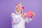 Portrait of attractive bearded cheerful grey-haired man in kigurumi holding heart amour isolated over violet purple