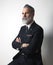 Portrait of attractive bearded middle aged gentleman wearing trendy suit over empty gray background. Studio shot