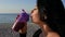 Portrait of an attractive brunette girl drinking a protein shake from a sports bottle on the background of the sea at sunrise.