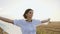 Portrait of the attractive brunette in long dress with light scarf running around the field of bales with raising hands