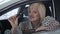 Portrait of attractive Caucasian senior woman sitting in car and showing keys at camera. Excited successful