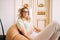 Portrait of attractive caucasian young woman in eyeglasses sitting on armchair in bright living room near ornamental door