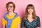 Portrait of attractive cheerful couple sister brother weird guy pretty woman isolated over pink pastel color background